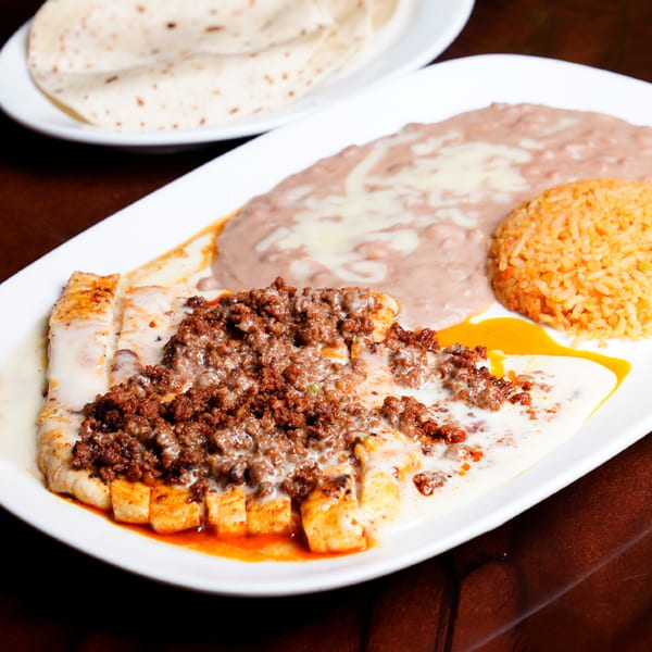 Grilled chicken topped with ground beef, cheese sauce, refried beans, rice, and tortillas.