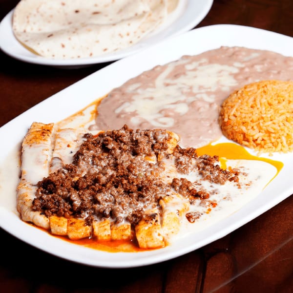 Grilled chicken topped with ground beef and cheese sauce, served with rice, refried beans, and tortillas.